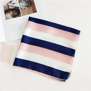 Close-up detail of the elegant pink, white, and navy blue striped silk square scarf flat lay.