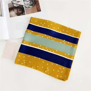 Detailed view of a stylish geometric striped and polka dot silk scarf in yellow and blue.