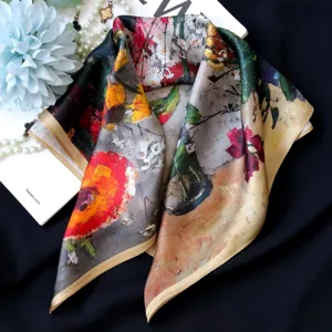 Close-up detail of luxury silk scarf featuring artistic oil painting floral print and gold edges.