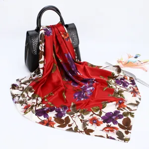 Close-up detail of the red satin floral print silk scarf draped over a black handbag display.