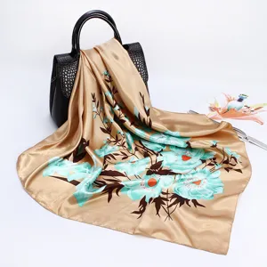 Detailed view of 90cm satin floral square scarf in champagne gold with turquoise flowers.