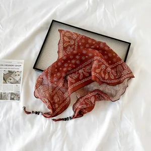 Detailed shot of a stylish brown paisley bandana scarf with delicate floral patterns and beaded ends.