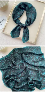 Dettaglio della sciarpa in seta verde scuro con stampa retrò, accessorio femminile elegante.