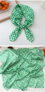 Close-up detail of green and white floral checkerboard silk square scarf texture.