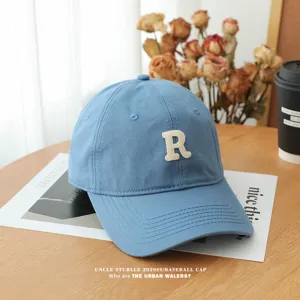 Detail view of the stylish blue cotton baseball cap featuring white R letter embroidery.