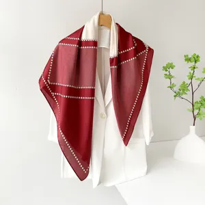 Close-up detail of elegant red and white satin square scarf with geometric diamond pattern.
