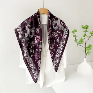 Close up view of dark purple satin square scarf with elegant floral print and lace border.