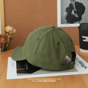 Detailed shot of army green cotton baseball cap with adjustable strap and soft crown on styled desk.