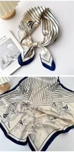 Detail view of a chic beige and navy blue striped silk scarf with elegant floral print.