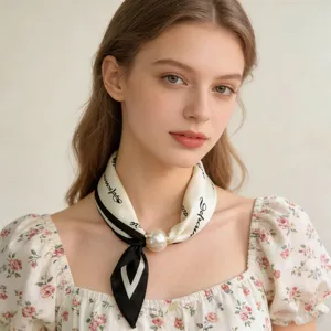 Close-up detail of elegant silk neck scarf with pearl magnetic clasp and striped trim.