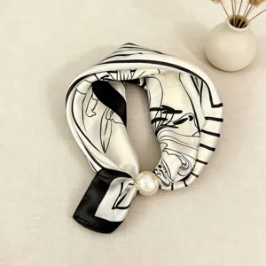 Close-up detail of the elegant black and white silk scarf with pearl magnetic clasp.