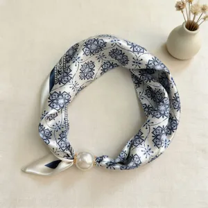 Close-up detail of blue and white geometric silk scarf featuring a pearl magnetic buckle.