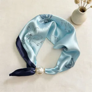 Detail shot of blue silk scarf with line art floral print and elegant pearl magnetic buckle.