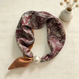 Silk scarf detail view, elegant paisley pattern with large pearl magnetic clasp accessory.