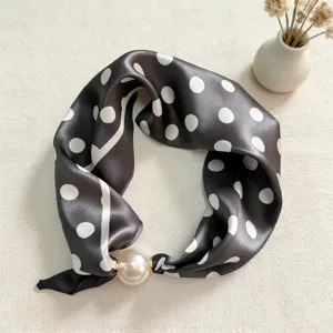 Detailed view of silk scarf with polka dots and pearl magnetic buckle for professional wear.