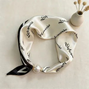 Elegant black and white silk scarf with letter print and pearl magnetic clasp accessory detail.