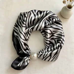 Detail shot of black and white zebra stripe silk scarf featuring a chic pearl magnetic clip.