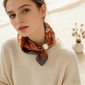 Dettaglio del foulard in seta paisley elegante con pratica fibbia magnetica di perla.