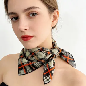 Close-up detail of geometric plaid scarf with striking orange and black contrast pattern.