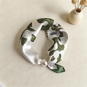 Detalle de pañuelo de seda fino primavera verano, estampado floral con hebilla magnética perla.