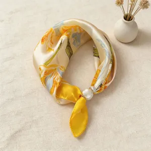 Primo piano del foulard in seta satinata con stampa floreale e dettaglio della fibbia di perla.