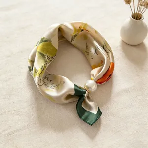 Dettaglio di un elegante foulard in satin con motivi astratti e una raffinata fibbia di perle.
