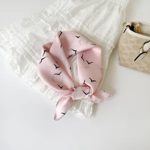 Detailopname van roze zijden sjaal met vogelmotief, ideaal als stijlvolle halsdoek en accessoire.