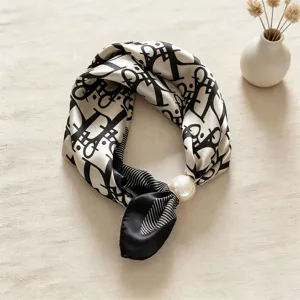 Primo piano di foulard in seta nero e bianco con motivo monogramma di lusso e fibbia di perla.