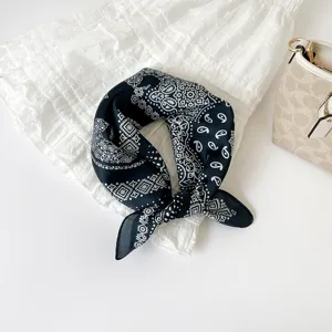 Detailweergave van een chique zwart-witte paisley print zijdezachte vierkante sjaal voor dames.