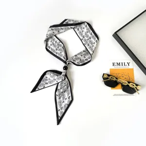 Detailed view of black and white paisley skinny twilly scarf with elegant black bead necklace.