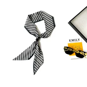 Detail view of a chic black and white striped skinny scarf featuring an elegant bead fastener.