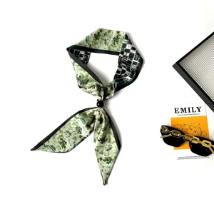 Detailed view of green printed silk twilly scarf with black ring and checkered pattern.
