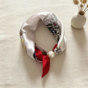 Dettaglio di foulard in seta elegante con motivi stampati rétro e anello di perla di lusso.