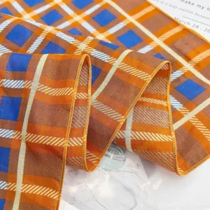 Detail shot of a vibrant orange and blue geometric cotton plaid scarf, stylish fabric texture.