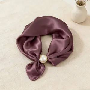 Dettaglio dell'elegante foulard in raso viola con grande chiusura magnetica di perle.