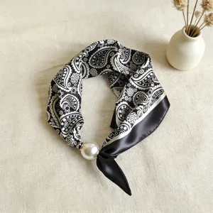 Detalle en primer plano del pañuelo de seda paisley en blanco y negro con cierre magnético perla.