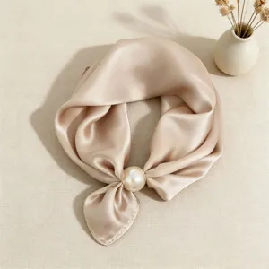 Vista dettagliata di un elegante foulard in raso beige con chic fibbia ad anello di perla.