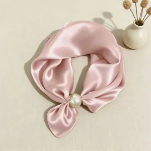 Dettaglio ravvicinato della elegante sciarpa in satin rosa con grande fibbia a perla.