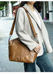 Close-up of brown leather patchwork shoulder bag showing fine texture and metal hardware.