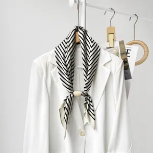 Detailed view of black and white striped silk scarf with wooden magnetic ring on white blazer.