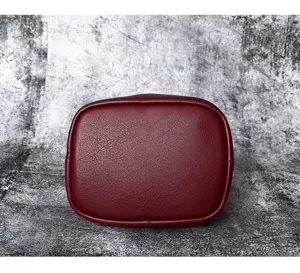 Detailed view of the burgundy leather bucket bag bottom showing fine texture and stitching.