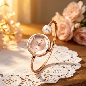 Nahaufnahme der eleganten roségoldenen Armbanduhr mit Perle und geometrischem Zifferblatt.