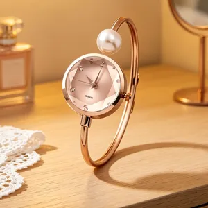 Detailansicht einer eleganten roségoldenen Armreif-Uhr mit Perle und facettiertem Zifferblatt.