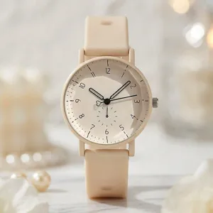 Nahaufnahme der minimalistischen cremefarbenen Uhr mit Silikonarmband und arabischen Ziffern.