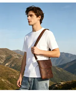 Detailed shot of a stylish men's genuine leather messenger bag worn outdoors with a casual outfit.