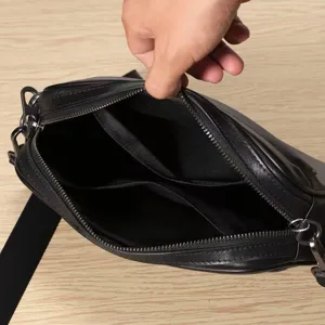 Detailed view of black genuine leather men shoulder bag interior compartments and zipper.