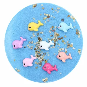Macro shot of colorful mini resin dolphins on blue sand for DIY micro-landscapes