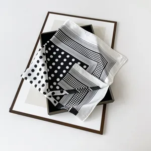 Nahaufnahme des eleganten schwarz-weißen Polka-Dot und gestreiften Satinseidentuchs.