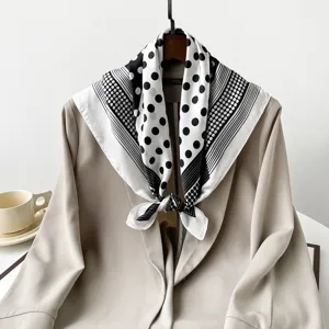 Vue détaillée d'un élégant foulard carré en satin à pois noirs et blancs sur veste.