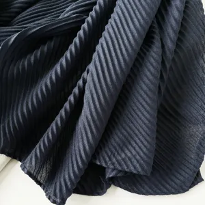 Detailed close-up view of a navy blue pleated scarf highlighting its fine plissé texture